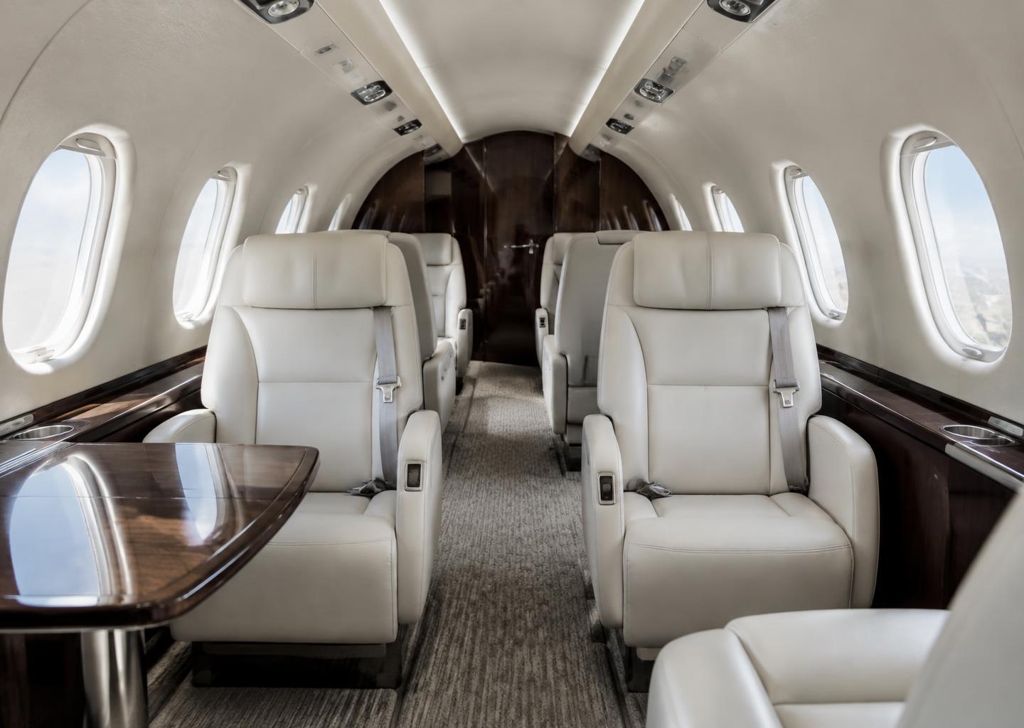 Illustrative private jet cabin with ivory leather seating and walnut trim
